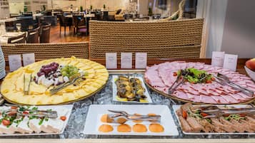 Ein Buffet mit verschiedenen kalten Speisen, darunter Käse, Fleisch und Salaten, präsentiert auf einer мраморна Theke mit Eis.