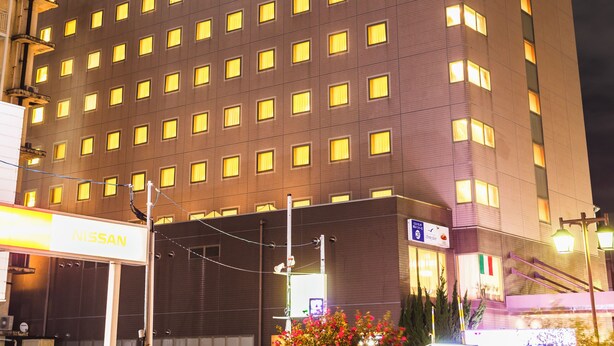 A tall hotel with a uniform facade and numerous illuminated windows. - Hotel Sunroute Niigata (Niigata)