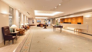A hotel lobby with a reception desk, seating area with chairs and tables, and a carpeted floor. - Hotel Sunroute Niigata (Niigata)