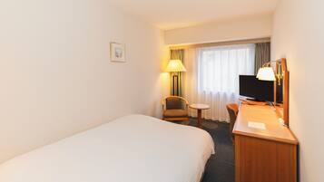 Une chambre d’hôtel avec un lit simple, un bureau avec une chaise, une télévision et une lampe.