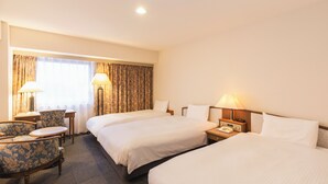 A hotel room with two beds, a desk with a chair, a lamp, and a telephone. - Hotel Sunroute Niigata (Niigata)