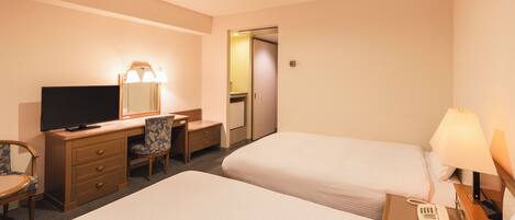 A hotel room with two beds, a desk with a chair, a television, a lamp, and a phone on the nightstand.