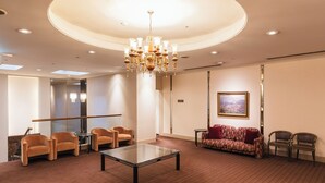A spacious lobby with a glass coffee table, multiple seating options including sofas and chairs, a chandelier, and a painting on the wall. - Hotel Sunroute Niigata (Niigata)