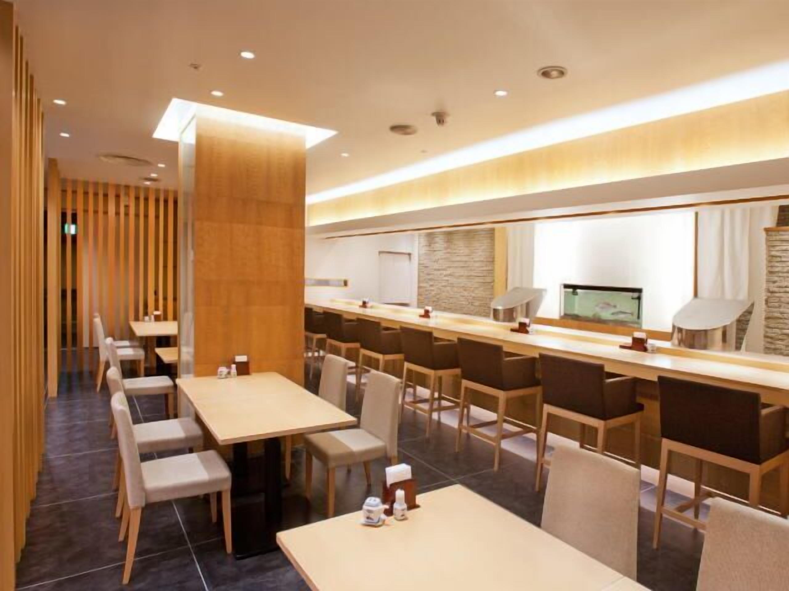 A modern hotel lobby with a long reception desk, multiple seating areas, and a stone accent wall.