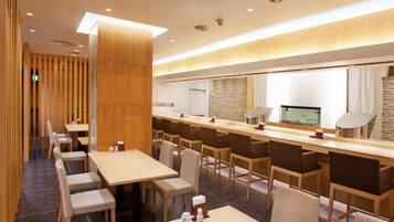 A modern hotel lobby with a long reception desk, multiple seating areas, and a stone accent wall.