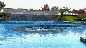 Een zwembad met een waterval en een bakstenen muur op de achtergrond.