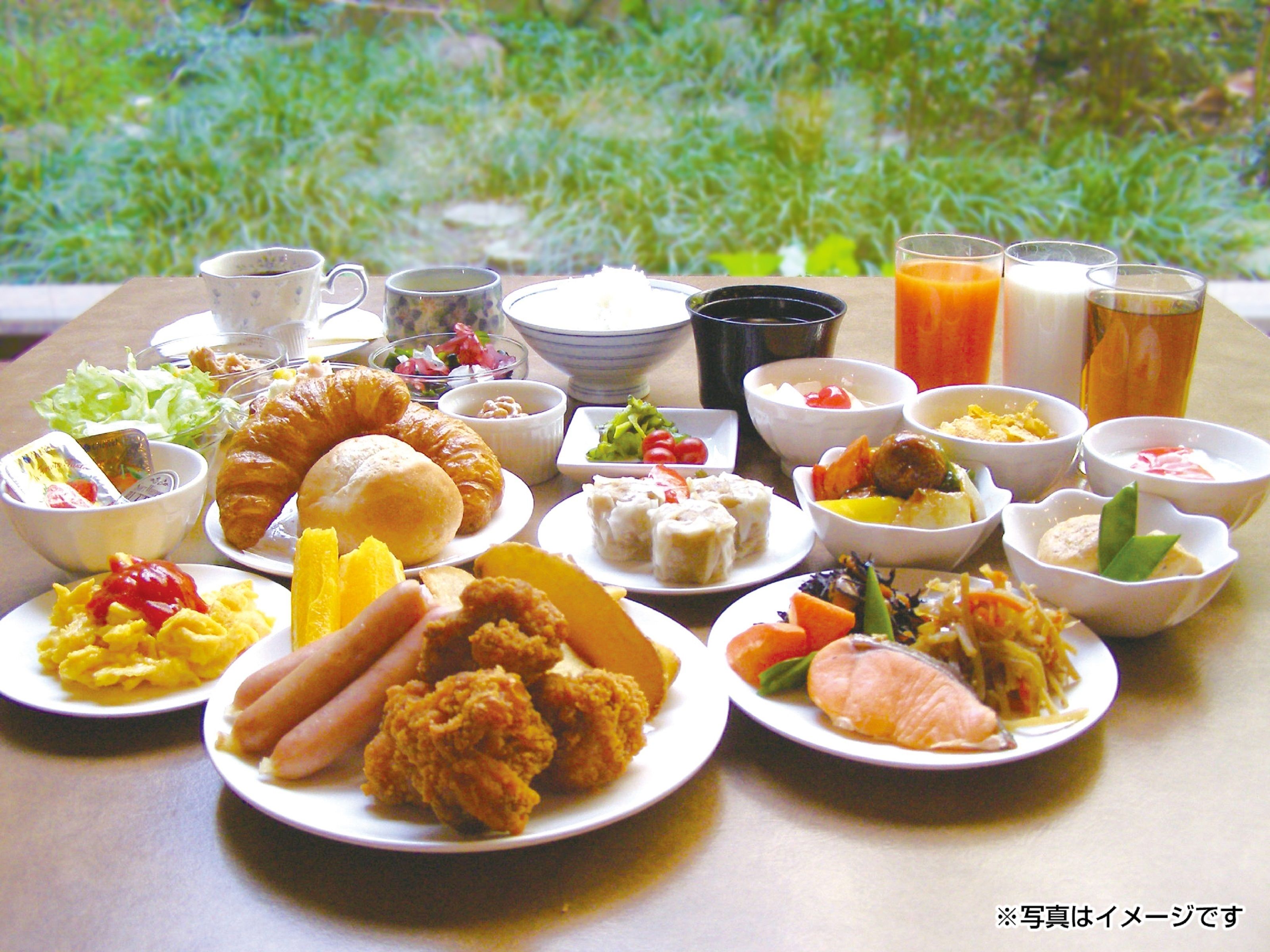A table with various dishes including croissants, salads, and meat dishes, along with drinks and condiments.