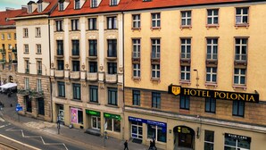 A multi-story building with a red-tiled roof, a sign for Hotel Polonia, and storefronts including a pharmacy and a hair care salon. - Hotel Polonia (Wroclaw)