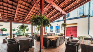 An outdoor patio area with wicker furniture, a wooden ceiling, and potted plants. - Hotel Polonia (Wroclaw)
