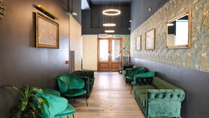 A hallway with green upholstered seating, a wooden floor, and framed artwork on the walls. - Hotel Polonia (Wroclaw)
