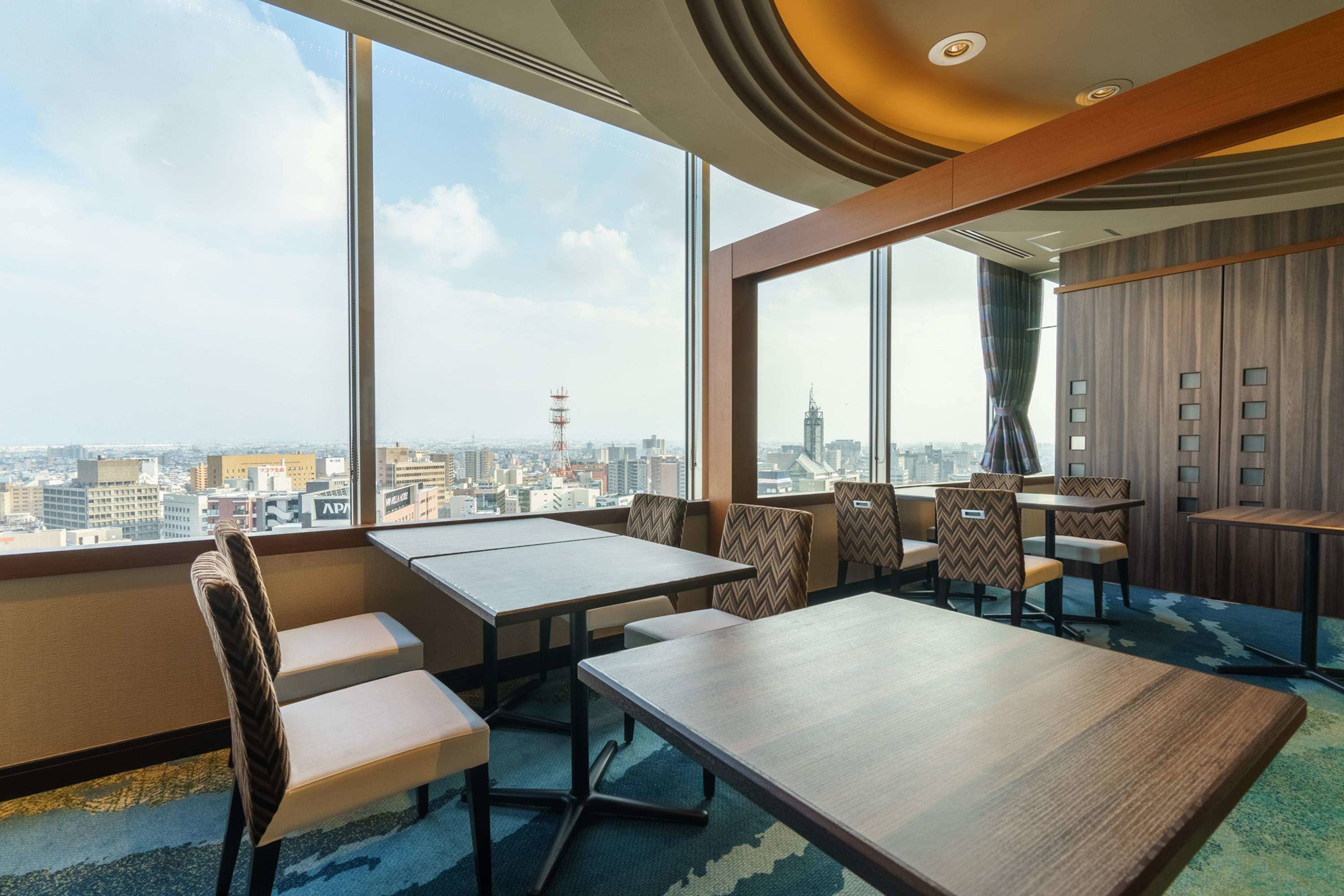 A modern conference room with large windows, a city view, and a mix of wooden and upholstered furniture.