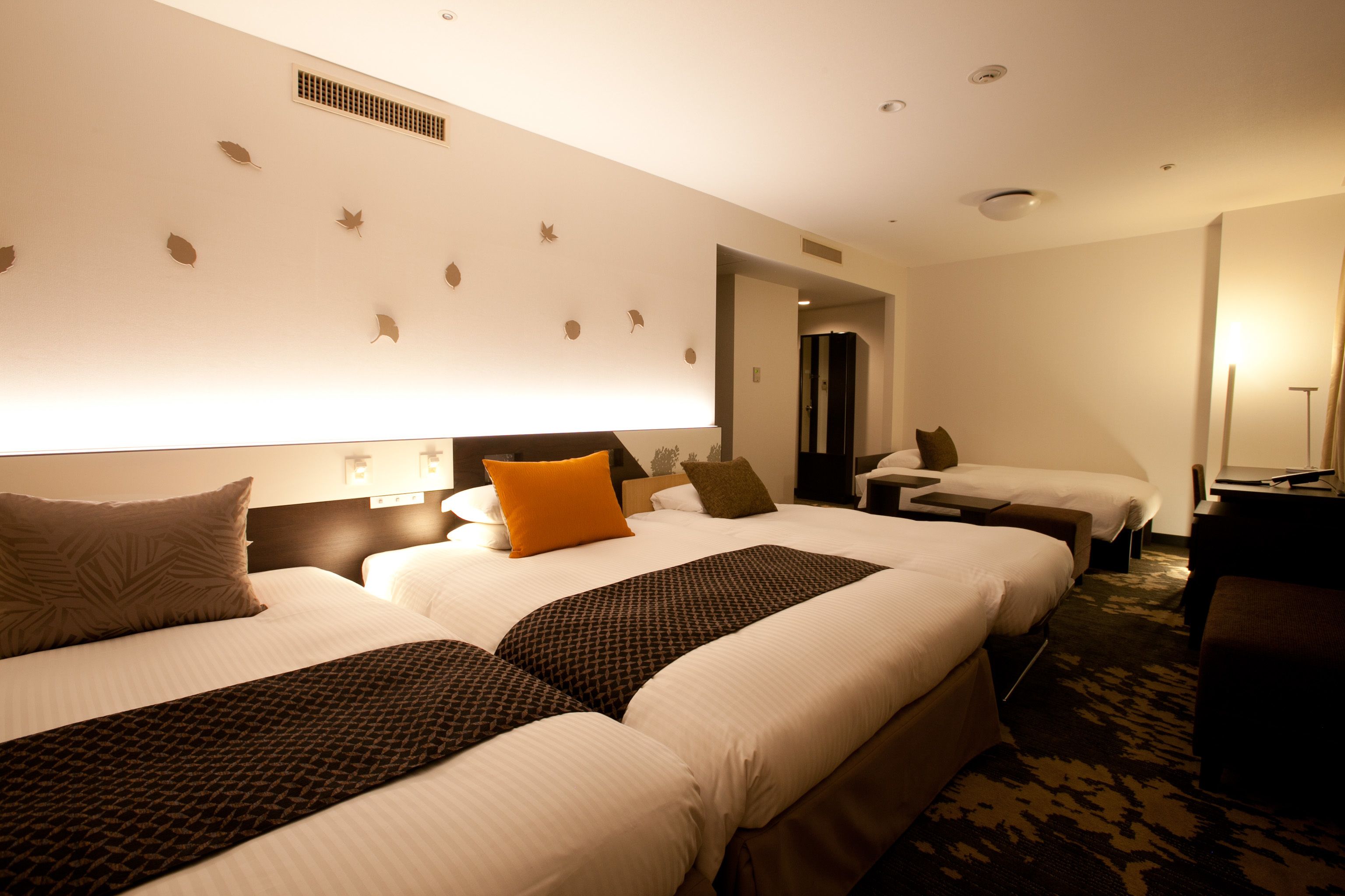 Une chambre d’hôtel avec deux lits, un bureau et une chaise.