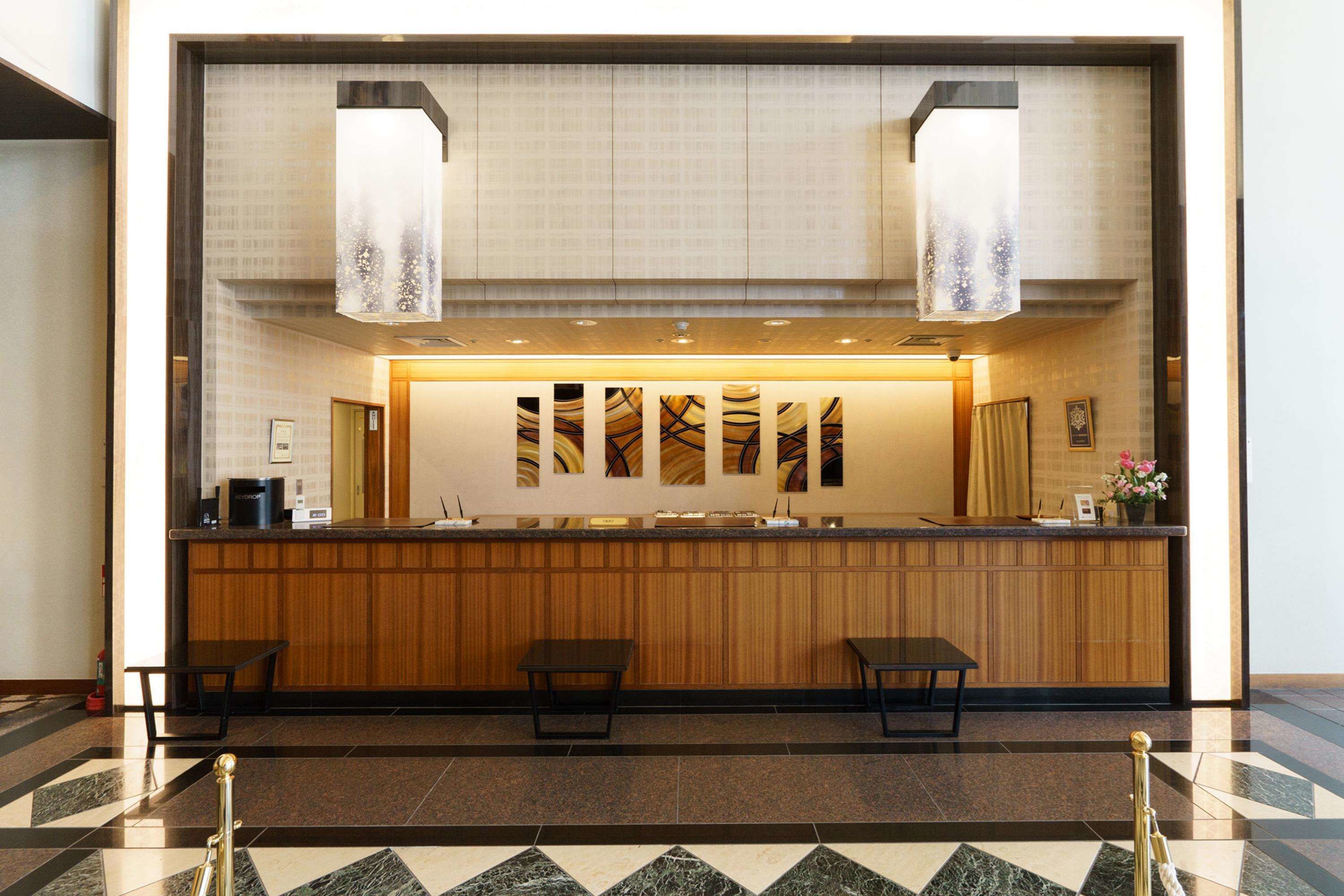 A reception area with a wooden counter, two seating areas, and a patterned wall.