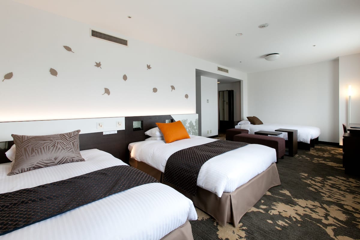A hotel room with three beds, a large mirror, and a carpeted floor.