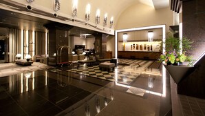 A spacious lobby with a checkered floor, modern furniture, and a central seating area.