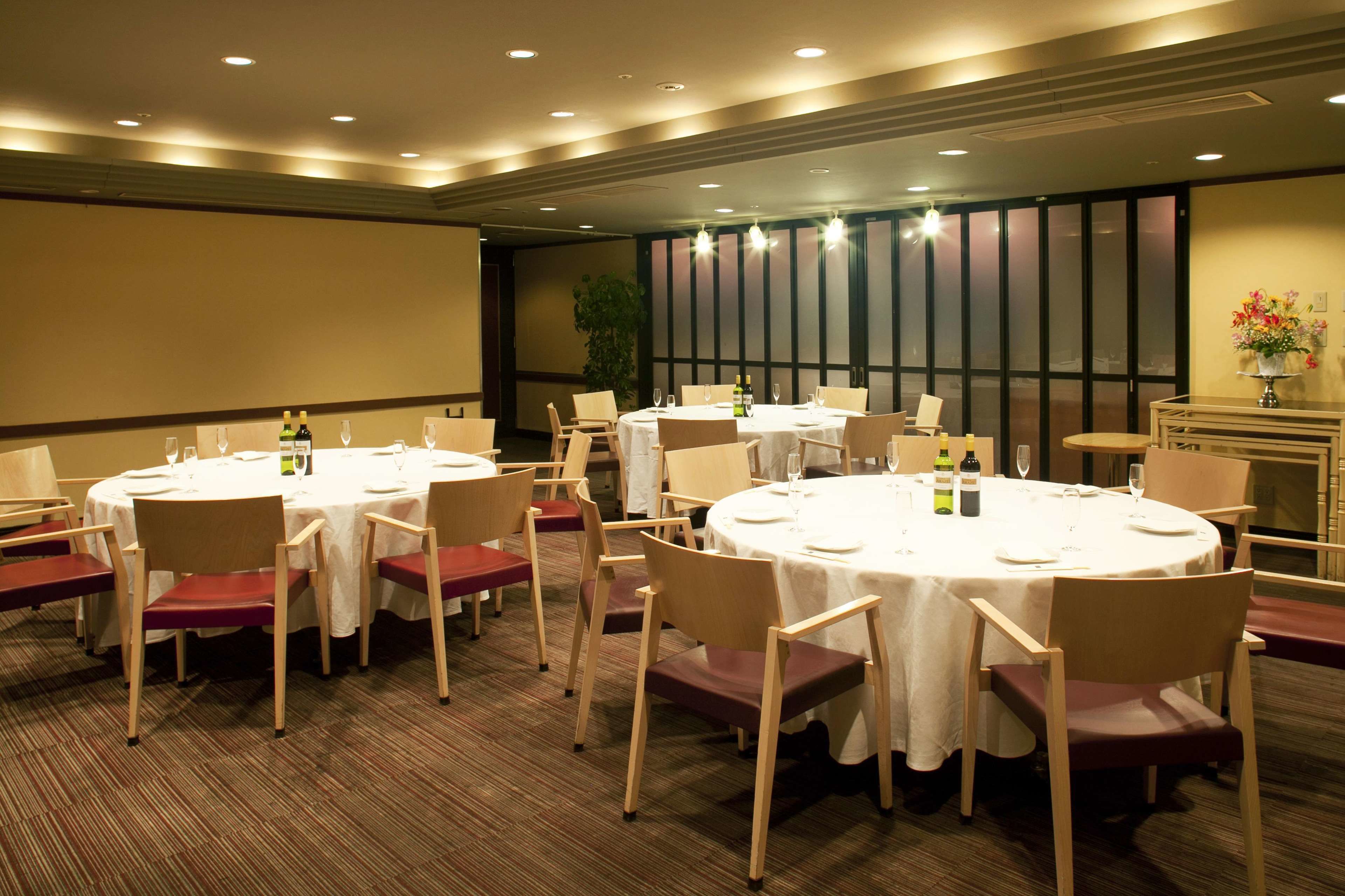 A conference room with round tables, chairs, and a projector screen.