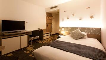 Een hotelkamer met een bed, een bureau met televisie, een stoel, een garderobe en een muur met visdecoraties.
