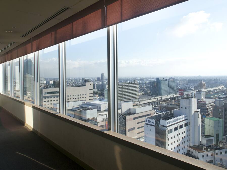 A high-rise hotel room with large windows offering a cityscape view.