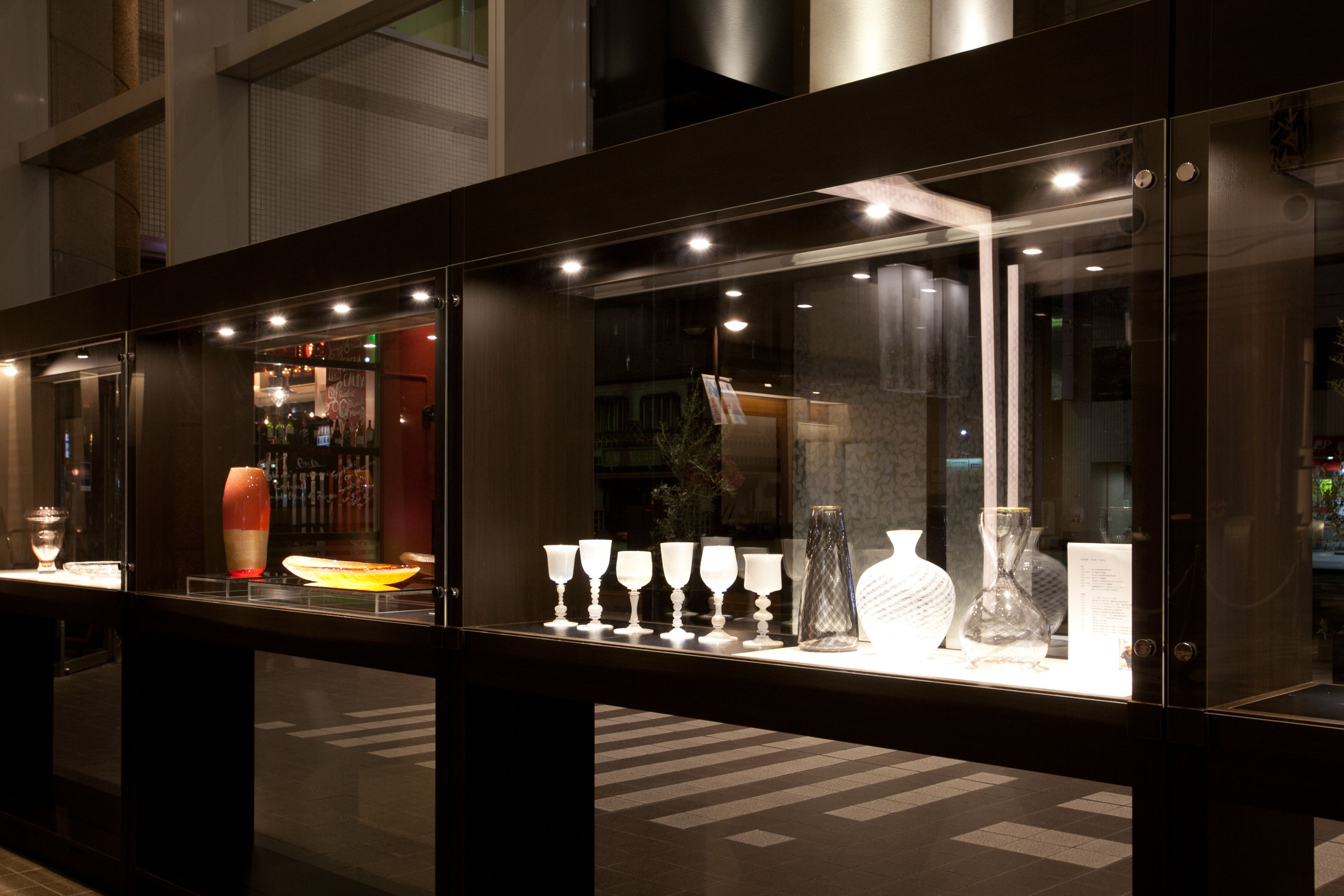 A glass display case with various glassware and a vase.
