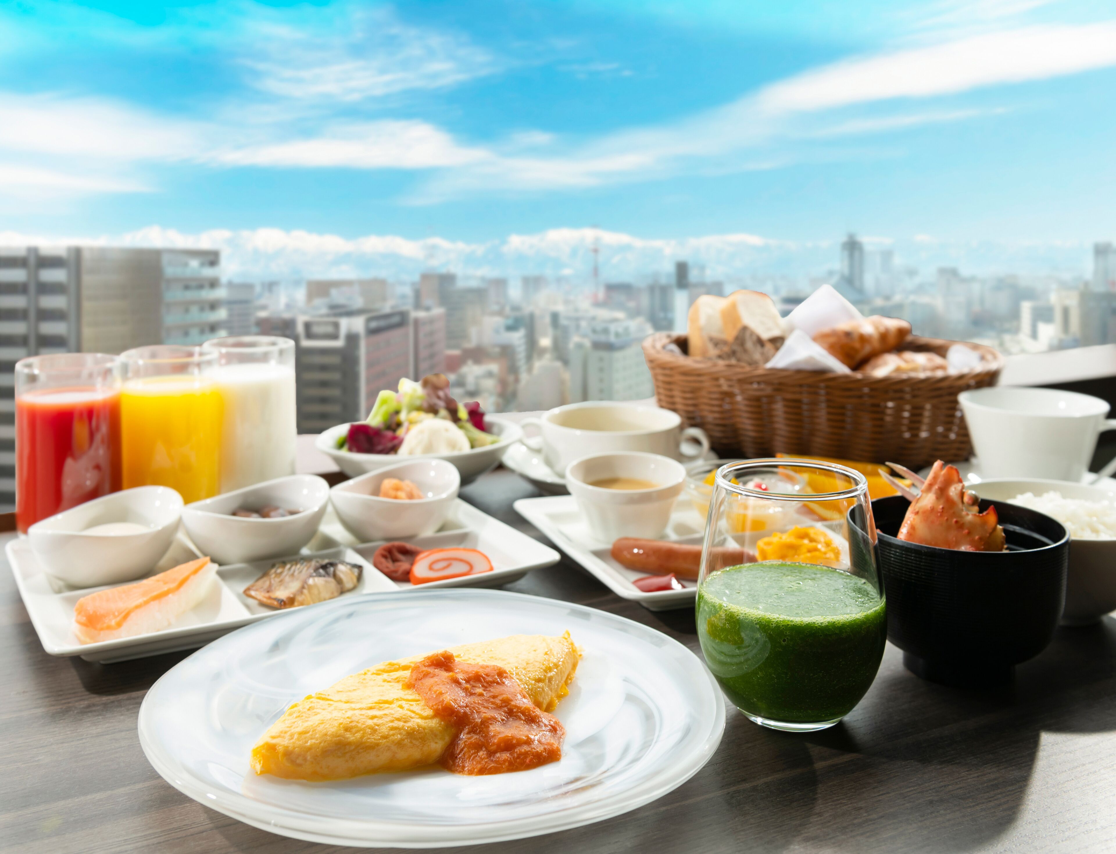 A breakfast table with various dishes, including eggs, soup, and juice, set against a cityscape view.