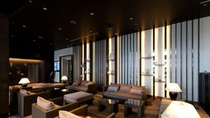 A modern lounge area with sofas, armchairs, and tables, featuring ambient lighting and vertical slats on the wall.