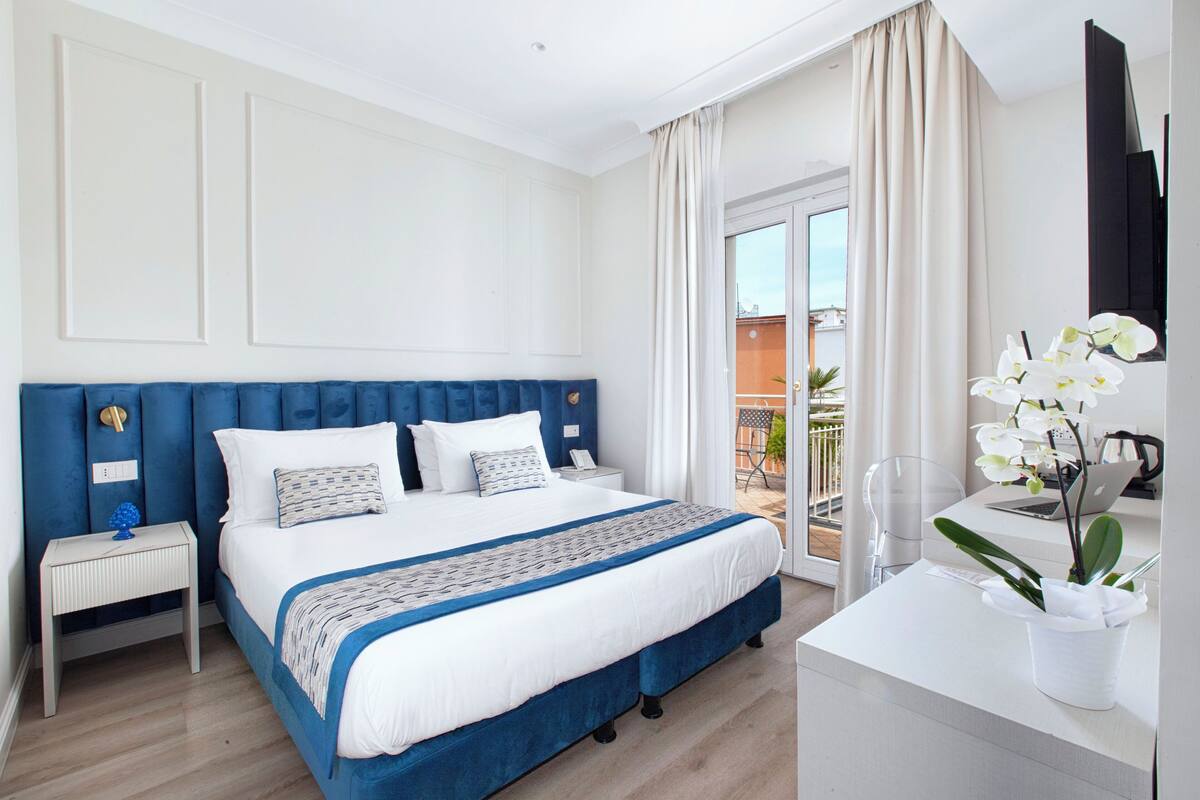 Une chambre d’hôtel avec un grand lit, un bureau et une vue sur l’extérieur.
