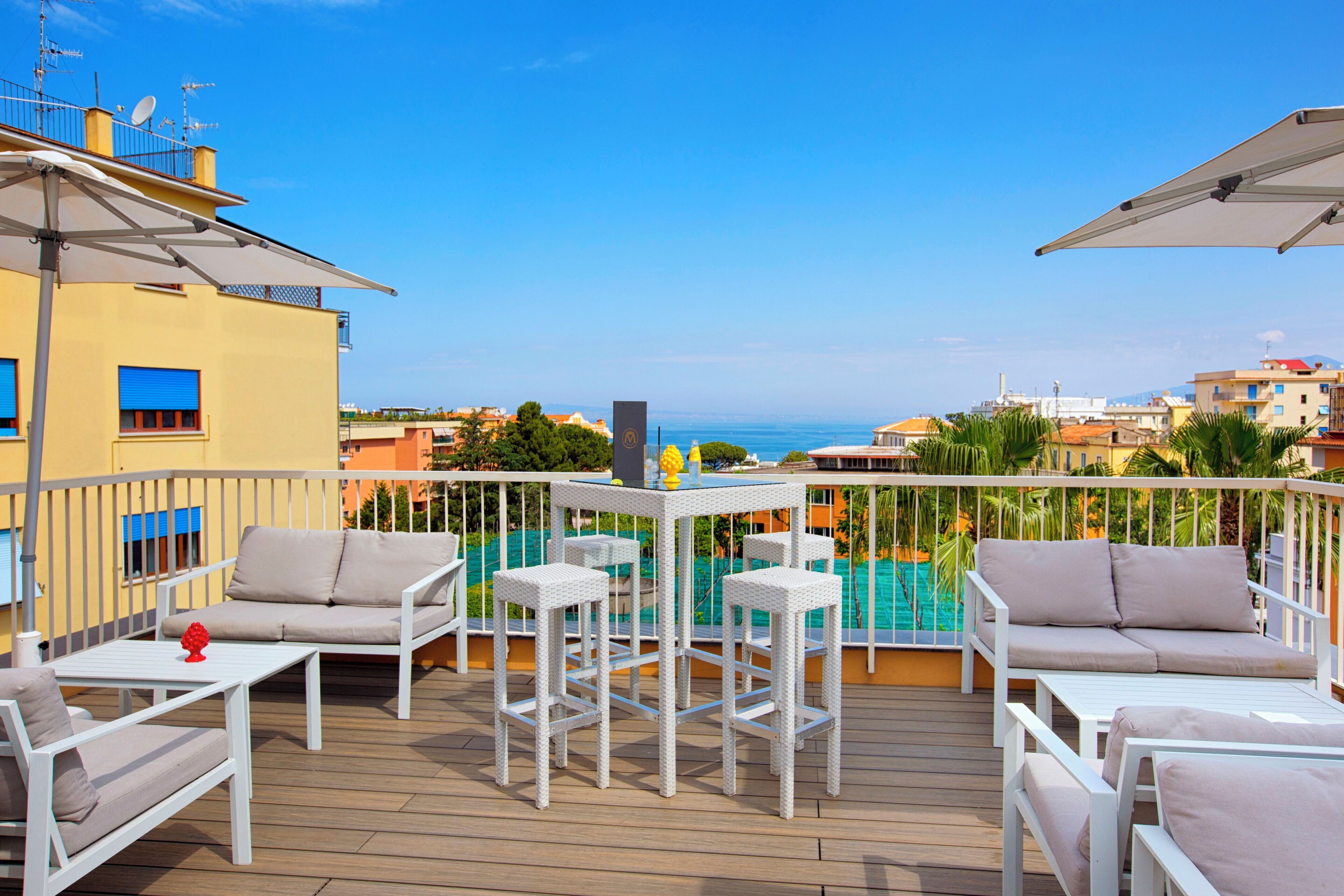A deck with outdoor furniture, a pool, and a view of the sea.