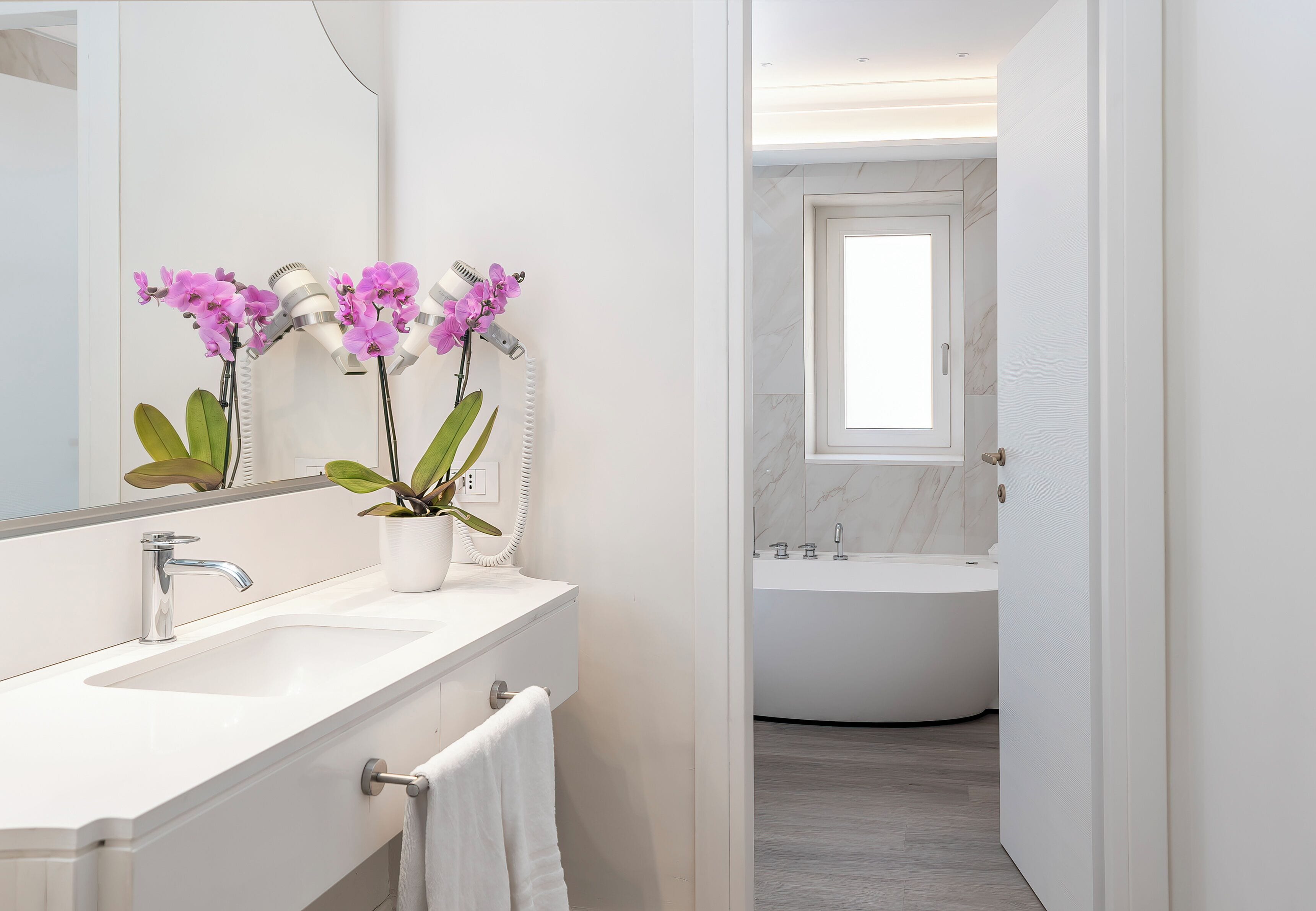 Ein modernes Badezimmer mit Waschbecken, Spiegel und Orchideenpflanzen.
