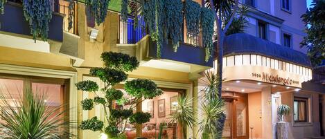 Un hotel con un jardín bien cuidado, un llamativo letrero 'Michelangelo' y un estilo arquitectónico europeo tradicional.