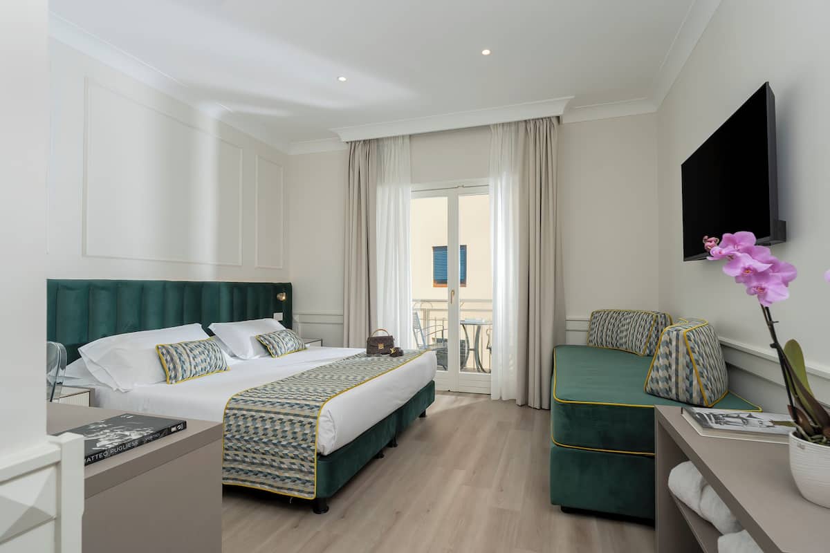 Une chambre d’hôtel avec un lit, une table de chevet, une chaise et une vue sur le balcon extérieur.