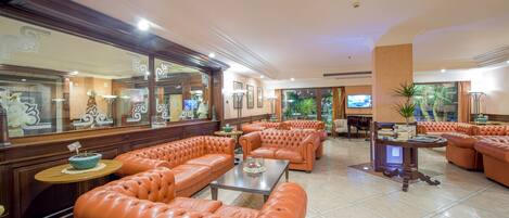 A spacious lobby with leather seating, a coffee table, and a television.