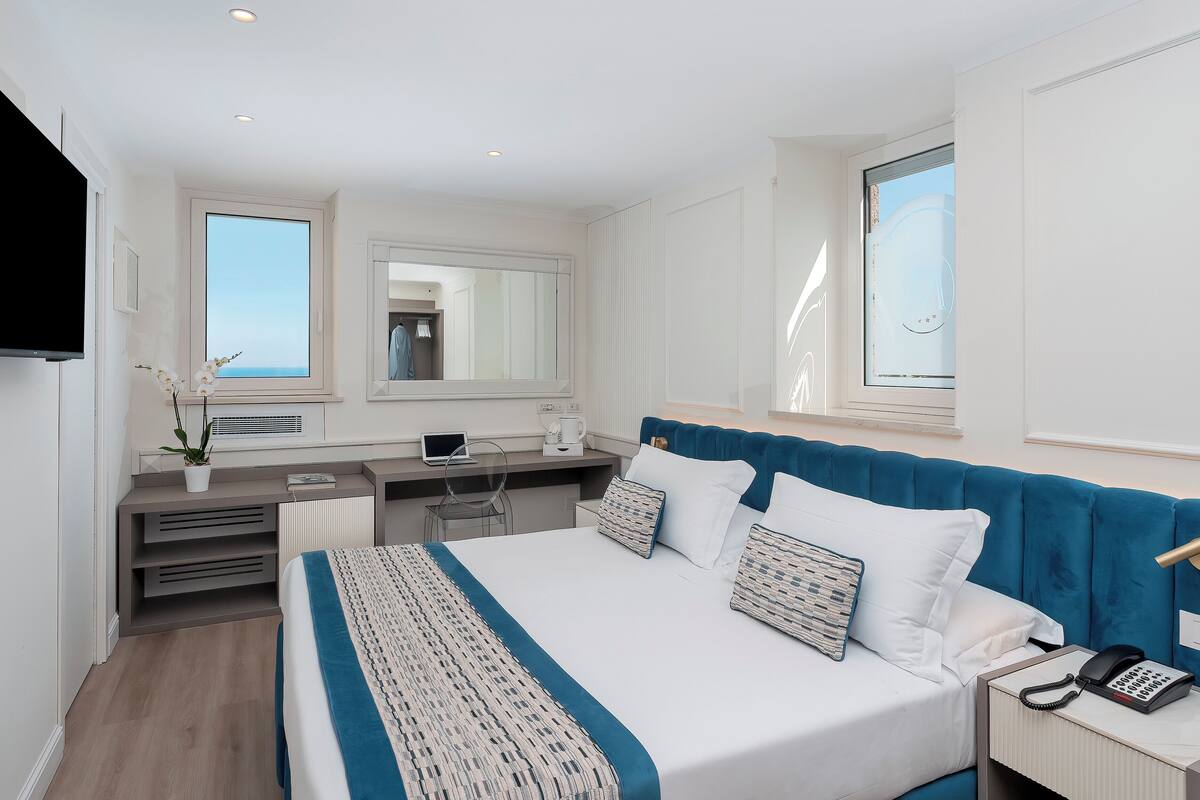 Une chambre d’hôtel moderne dotée d’un grand lit, d’un bureau, d’une chaise, d’un téléviseur à écran plat et d’une fenêtre offrant une vue agréable.