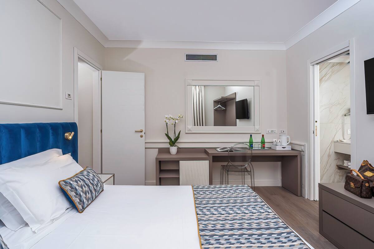 Une chambre d’hôtel moderne équipée d’un lit, d’un bureau, d’un miroir et d’une salle de bain.
