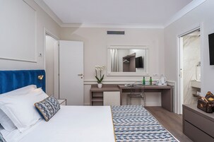 Una habitación de hotel moderna con una cama, un escritorio, un espejo y un baño.