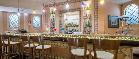 A bar area with a counter, bar stools, and shelves stocked with bottles.