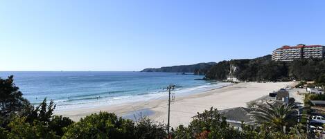 A beach with a hotel in the background.
