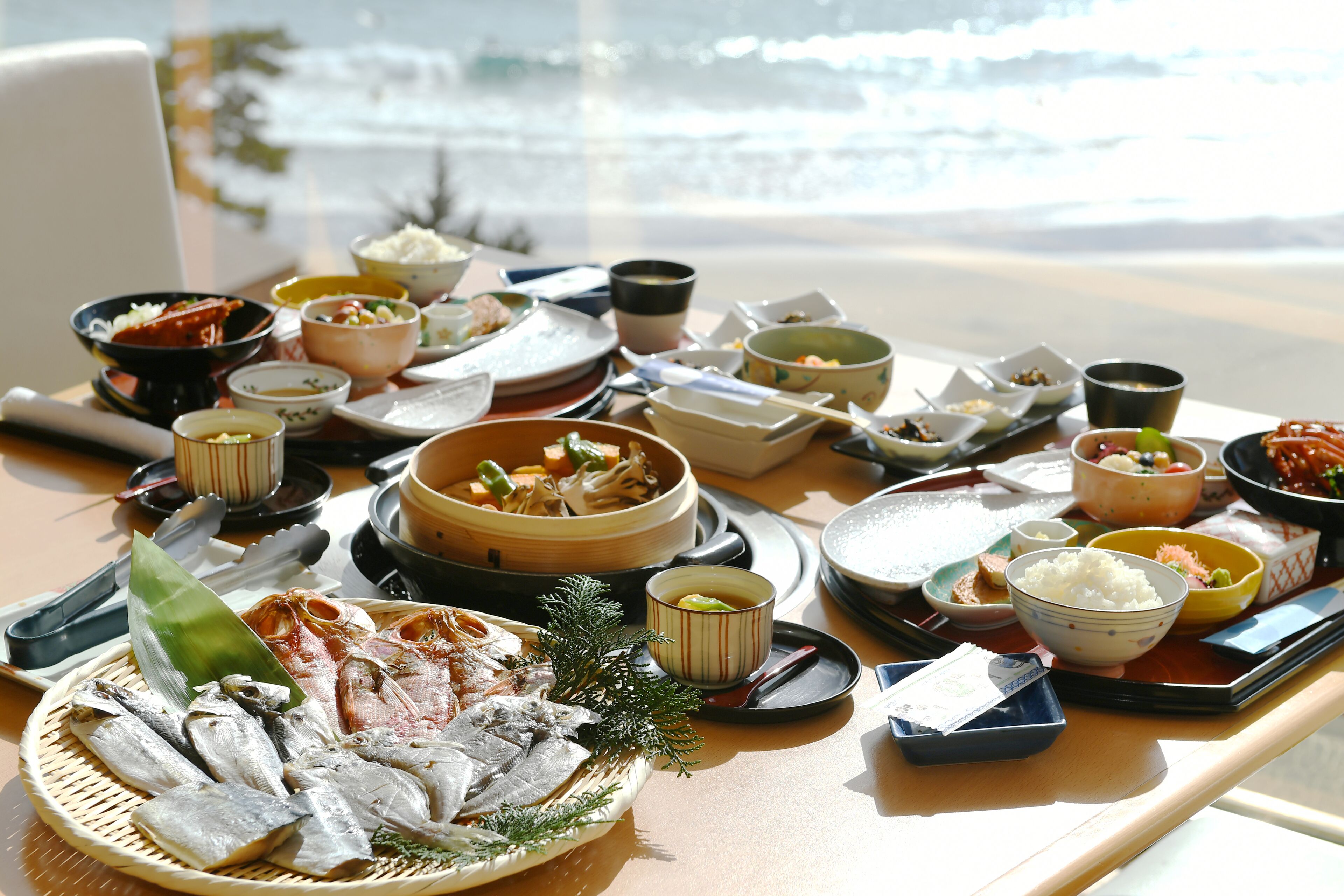 A table with various dishes and a view of the ocean.