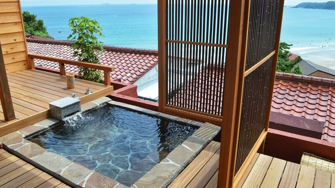 A hot tub on a wooden deck with a view of the ocean.