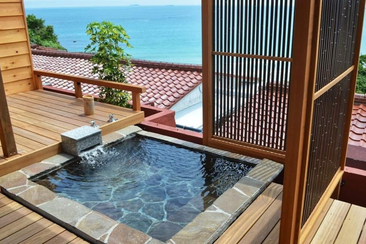 A hot tub on a wooden deck with a view of the ocean.