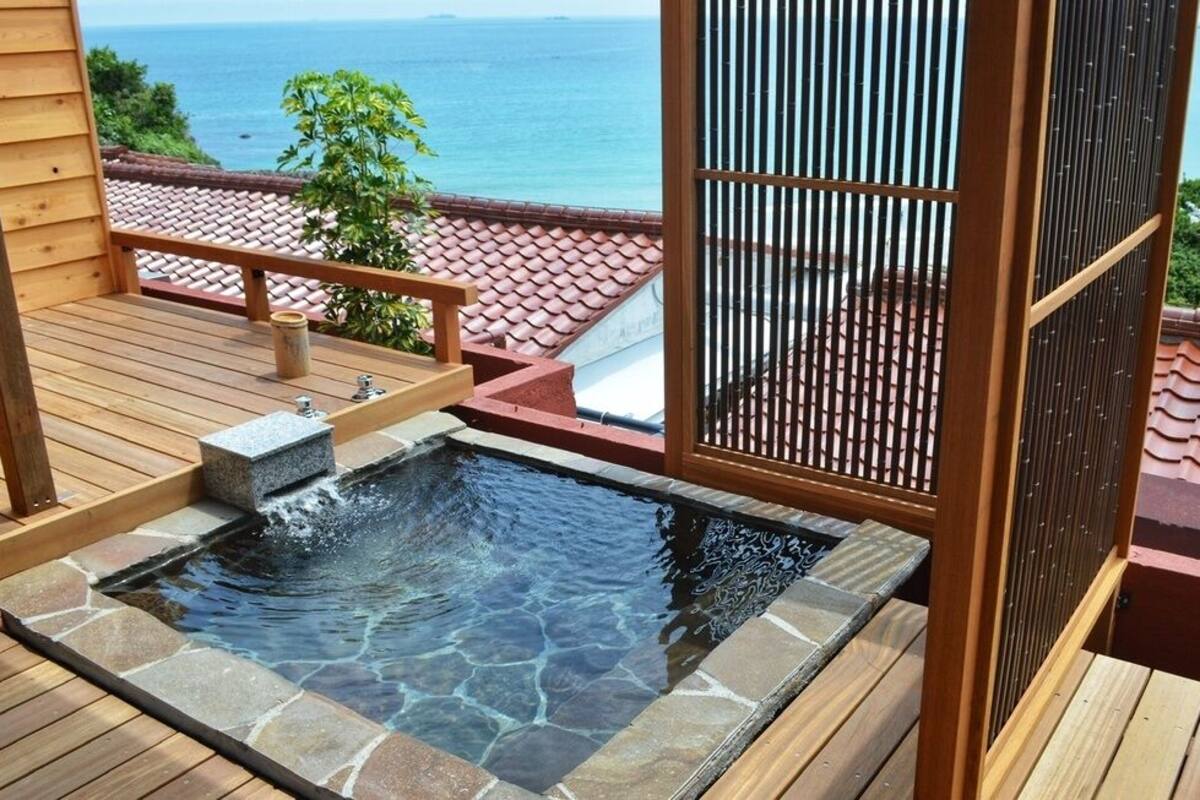 A hot tub on a wooden deck with a view of the ocean.