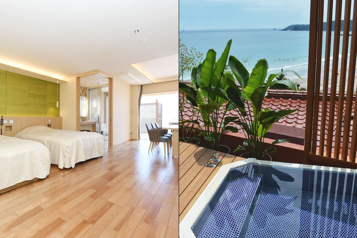 A hotel room with two beds, a wooden floor, a green wall, and a view of the sea.