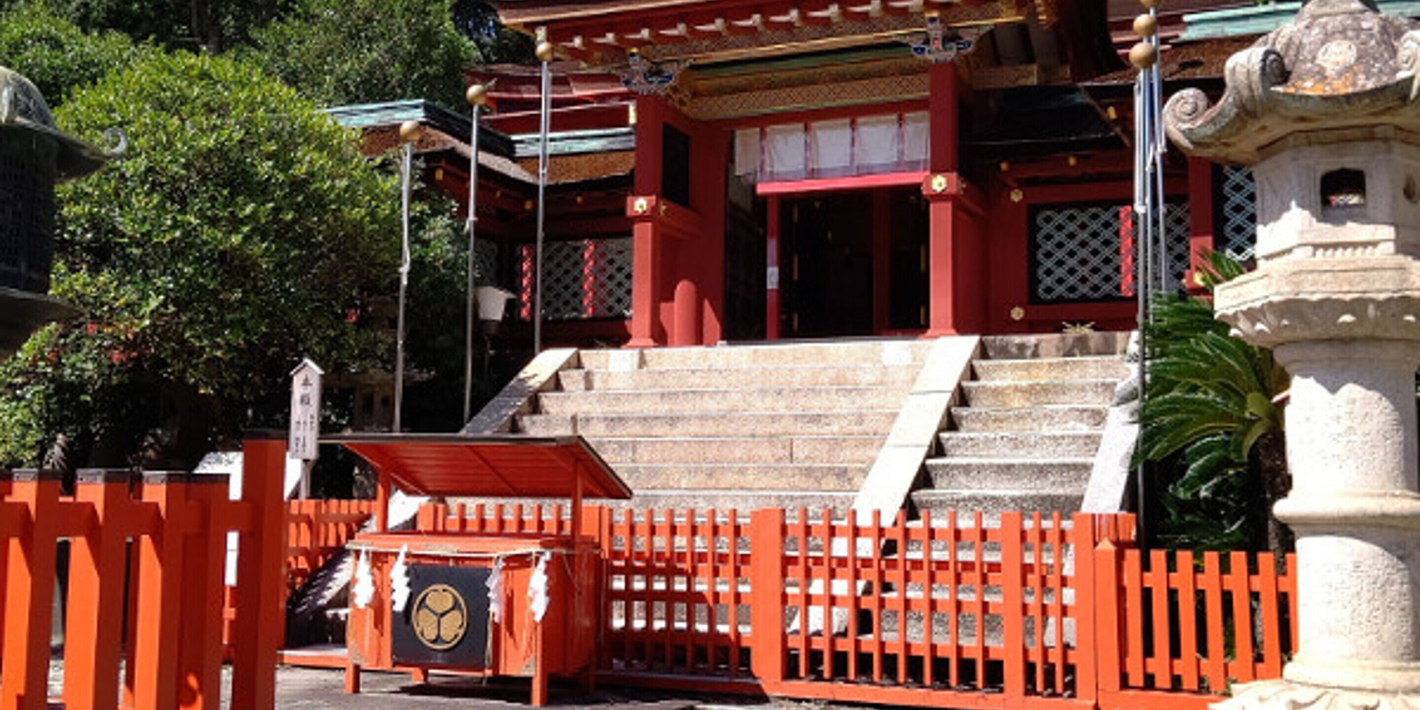 A traditional Japanese temple with a red torii gate, stone steps, and a stone lantern.