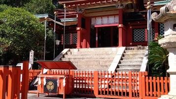 A traditional Japanese temple with a red torii gate, stone steps, and a stone lantern.