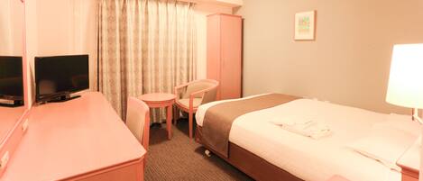 Une chambre d’hôtel comprenant un lit, un bureau avec une télévision, une chaise et une armoire.