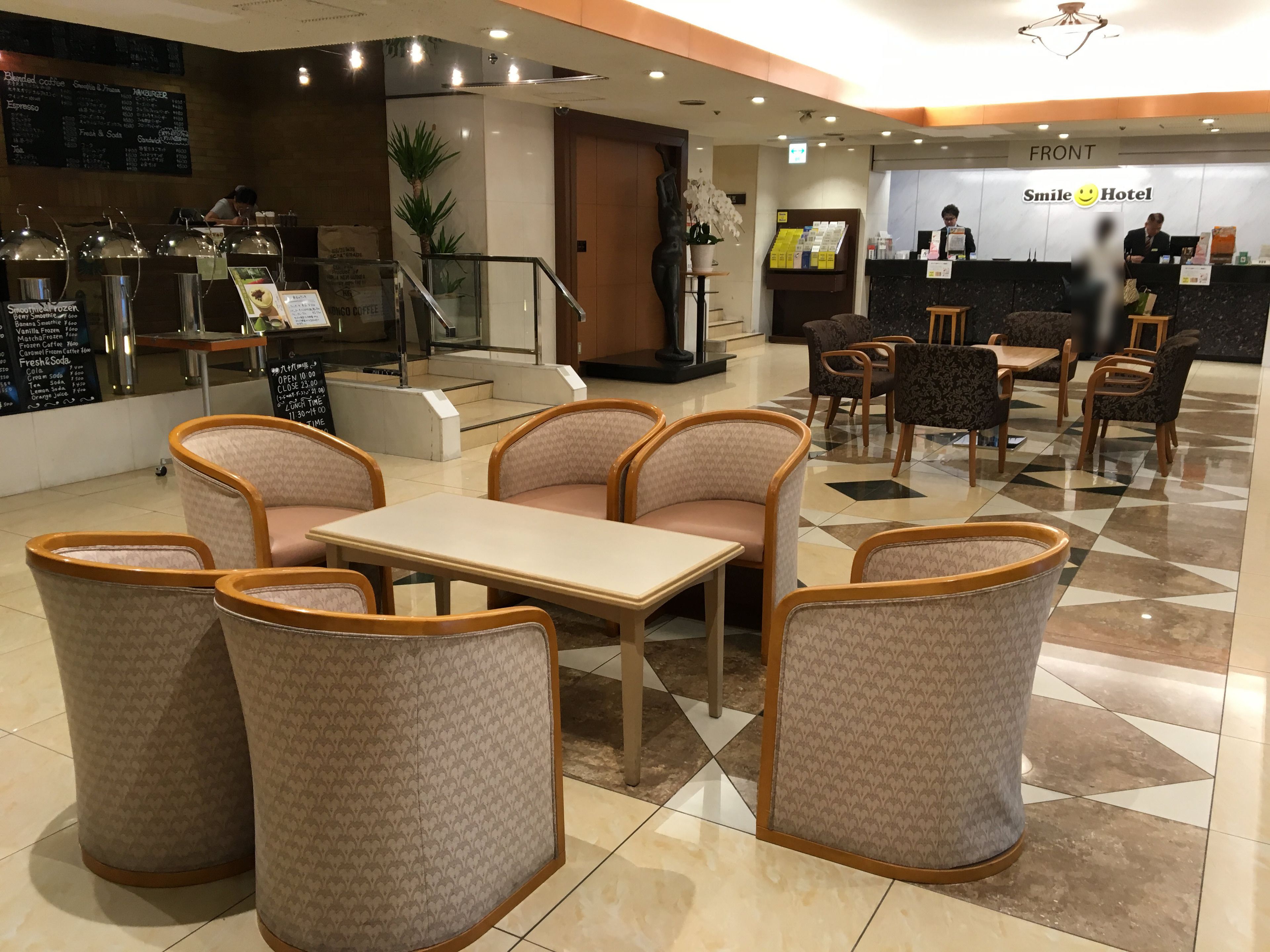 Un vestíbulo de hotel con zonas de estar, un mostrador de recepción y una estación de café.