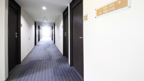 Ein langer, schmaler Hotelkorridor mit Türen, die mit den Nummern 501 bis 518 gekennzeichnet sind, was auf mehrere Zimmer hindeutet.