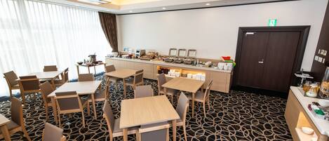 A hotel room with a dining area, a buffet counter, and a patterned carpet.