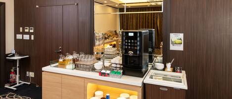 A hotel room with a minibar, a coffee machine, and a glass display case.