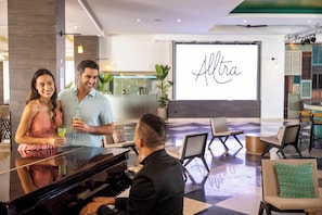 A hotel lobby with a grand piano, seating area, and a large screen displaying the word 'Altra'. - Sunscape Cancun Resort & Spa - All Inclusive (Cancun)