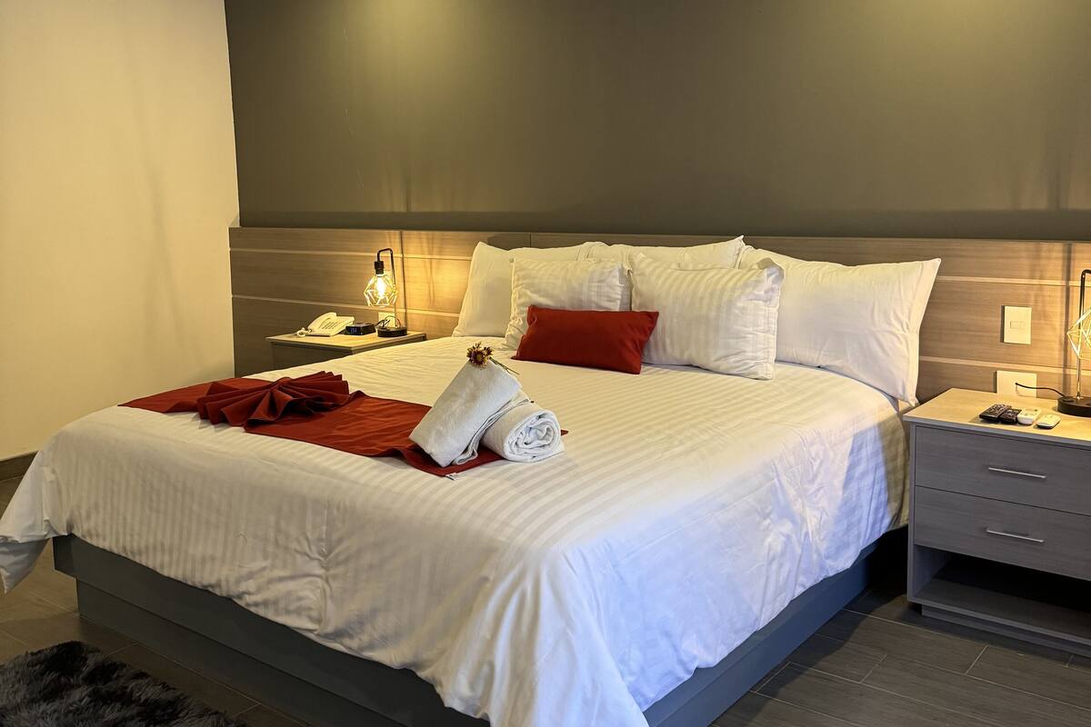 A modern bedroom with a large bed, bedside tables, and a nightstand.